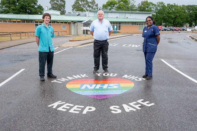 Three members of staff stood around road marking which says "keep safe"